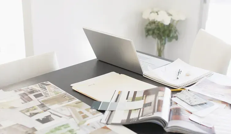 Laptop on desk with sample books and paint swatches