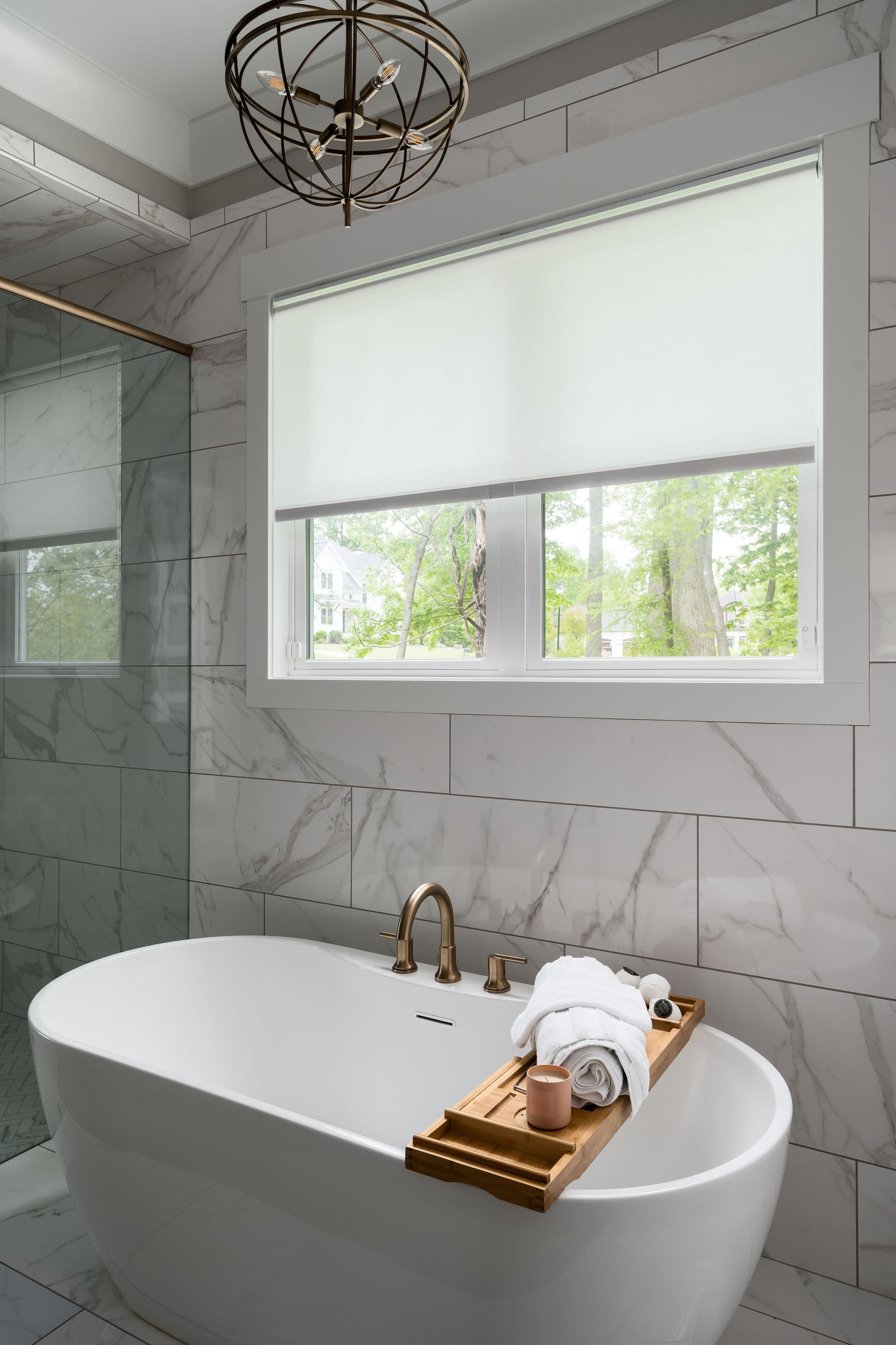White roller shade in bathroom window above bathtub via Sunbrella