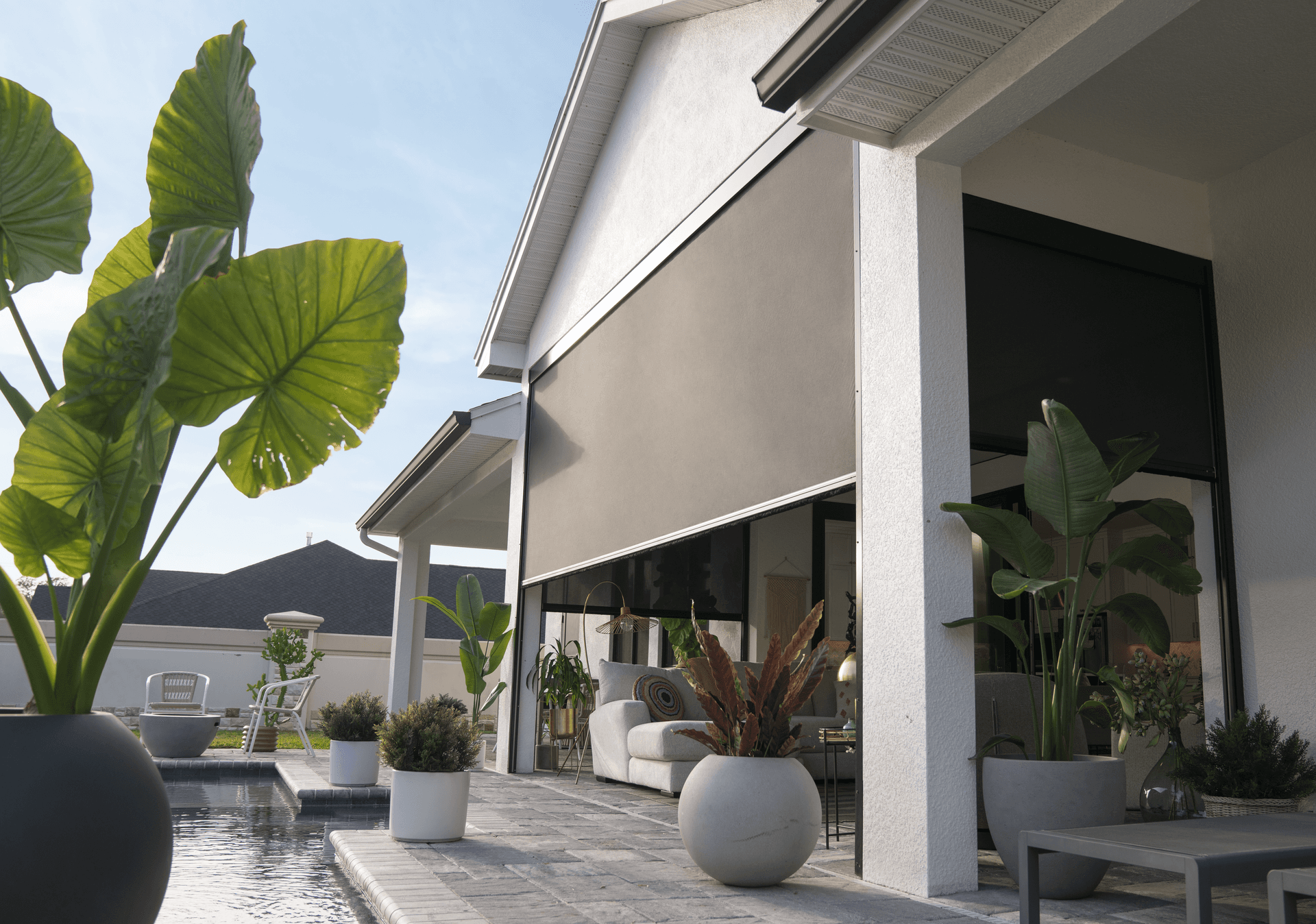 Partially opened EasyScreen screen system around an outdoor patio area next to a pool